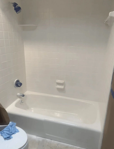 The same Daytona Beach bathtub and tile surround refinished in pure white, with blue tape still covering the shower head and valve