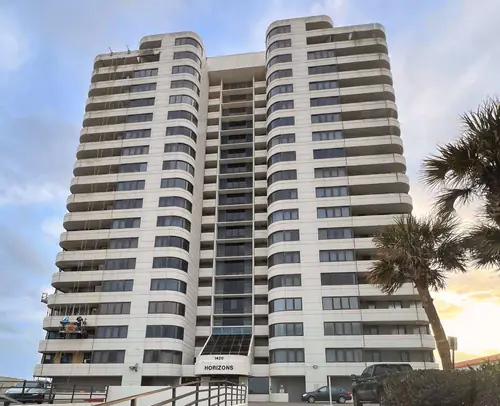 Oceanfront high rise in Daytona Beach during pressure washing and painting, with a suspended work platform on the left side of the building