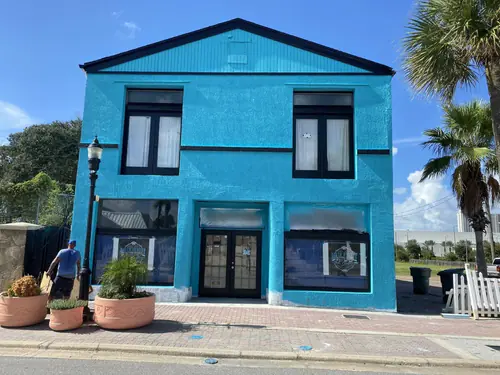 Two story commercial storefront in Volusia County painted bright aqua with black window trim