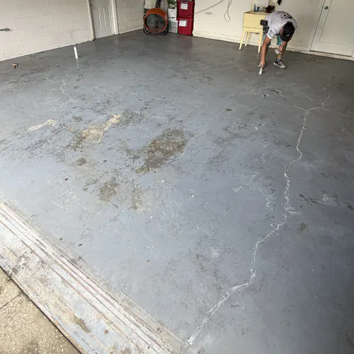 Stained and cracked garage slab in Daytona Beach with the crack being filled before coating