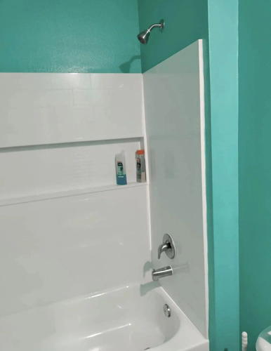Port Orange bathroom with freshly painted deep turquoise walls meeting a white tub and shower surround