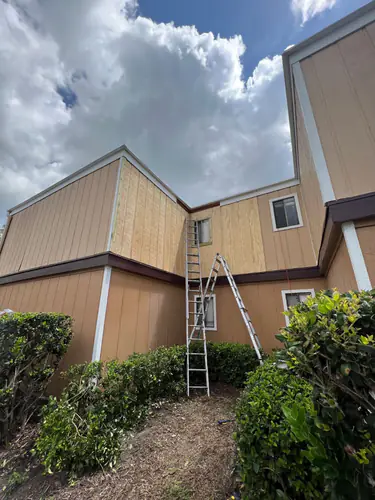 New construction apartment complex in Daytona Beach during painting, with bare siding and two ladders set against the wall