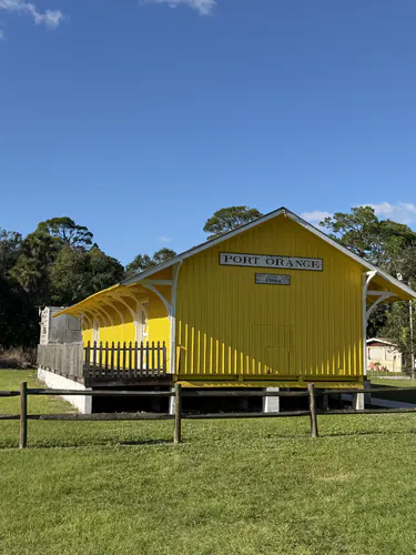 Gable end of the finished Port Orange depot, painted yellow with white fascia, under the Port Orange and FEC 1894 building signs