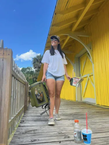 Color Masters crew member walking the depot platform during the job, carrying a paint pail past the yellow wall and a white trimmed freight door