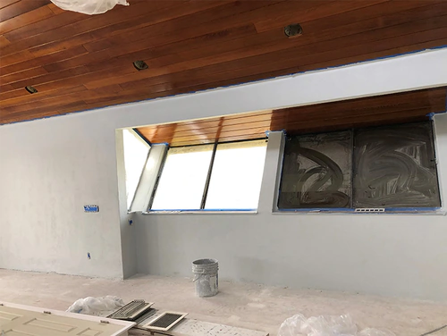 Port Orange room during interior painting, with light grey walls, masked skylight openings and a natural tongue and groove wood ceiling